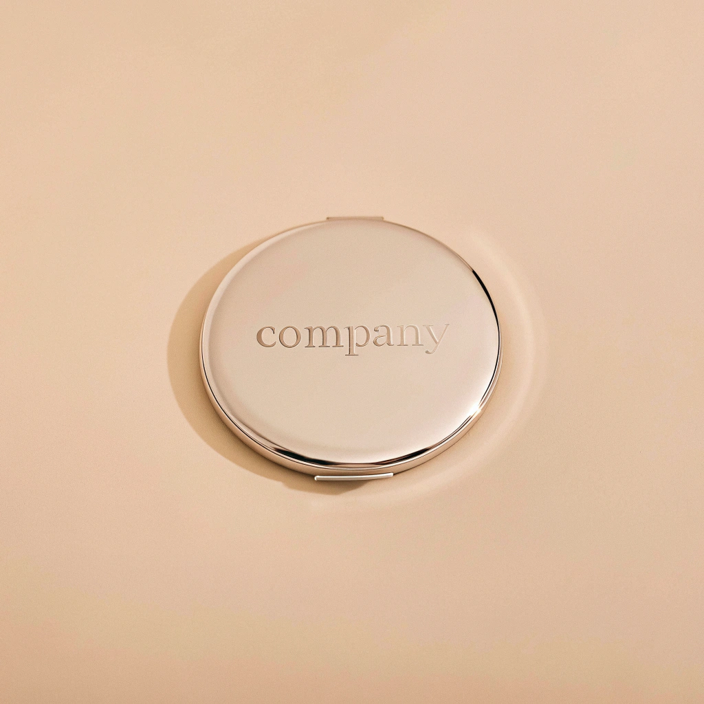a close-up of a promotional compact mirror showing a sophisticated company logo