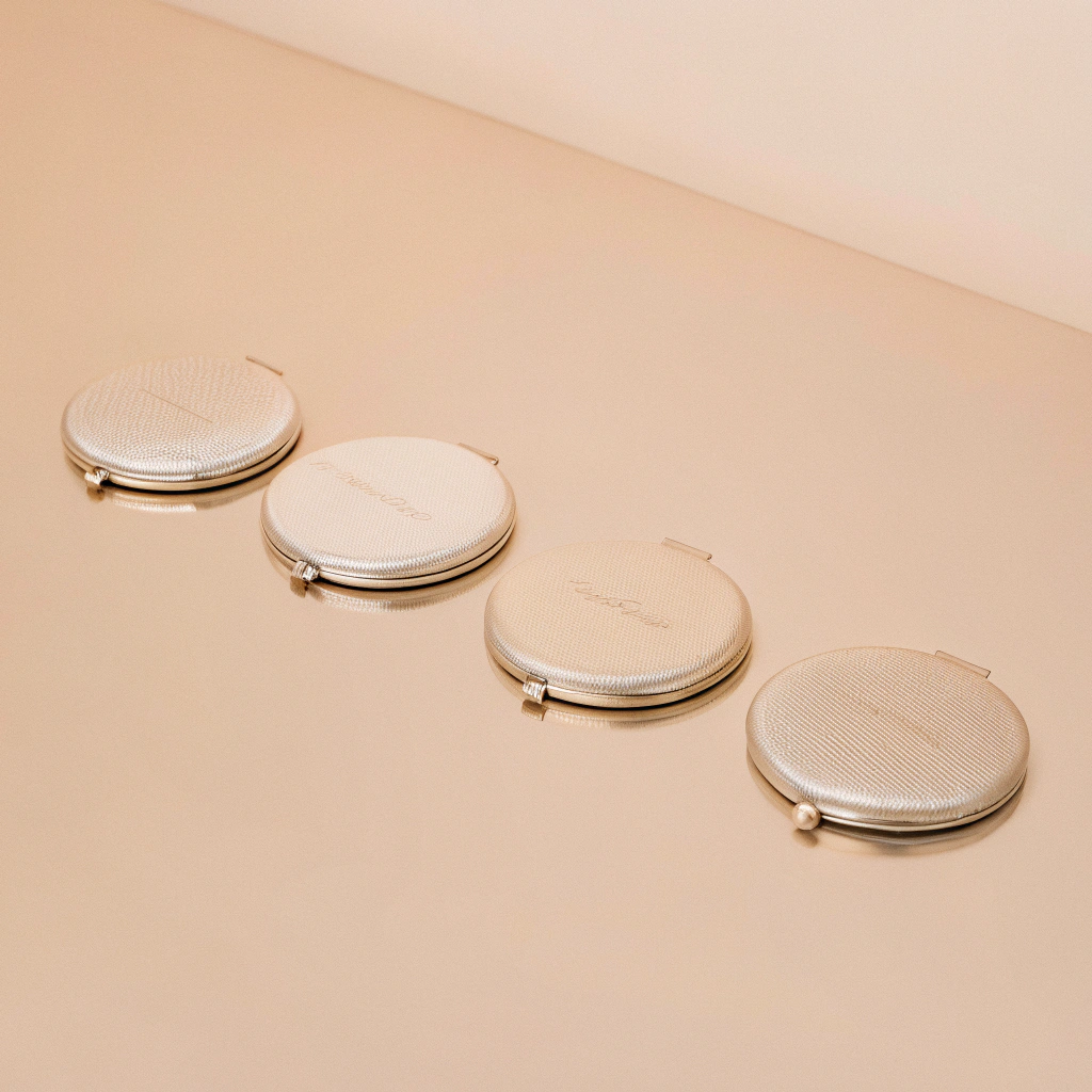 a collection of elegant custom compact mirrors with various business logos on display