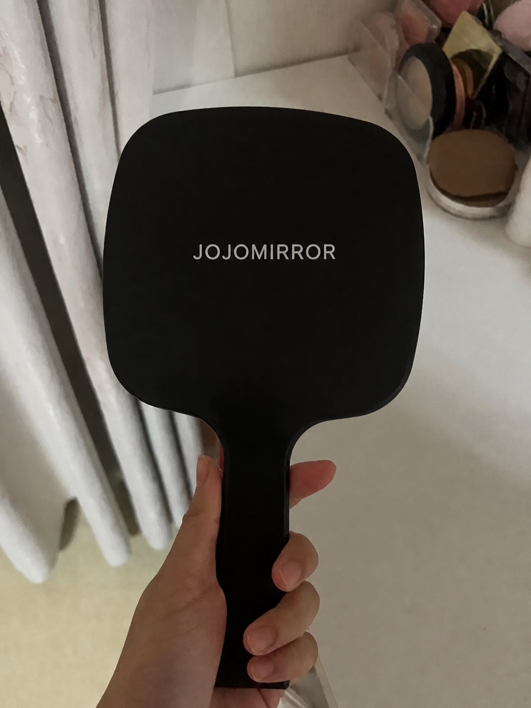 Back of a paid handheld mirror sample with replacement JOJOMIRROR branding